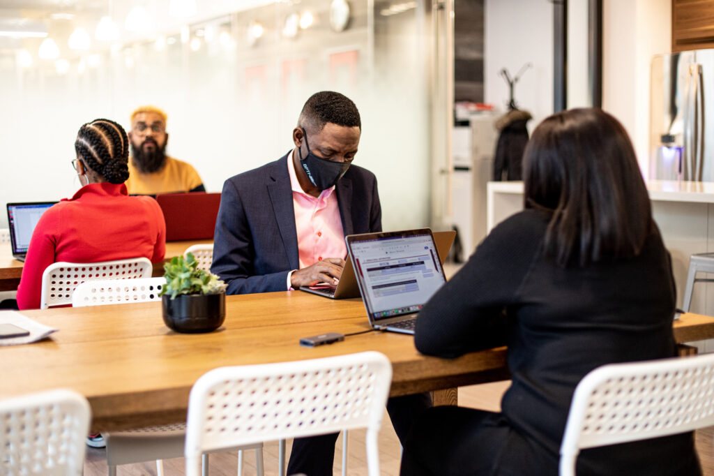 Four black professionals working at tables in co-working space in Toronto